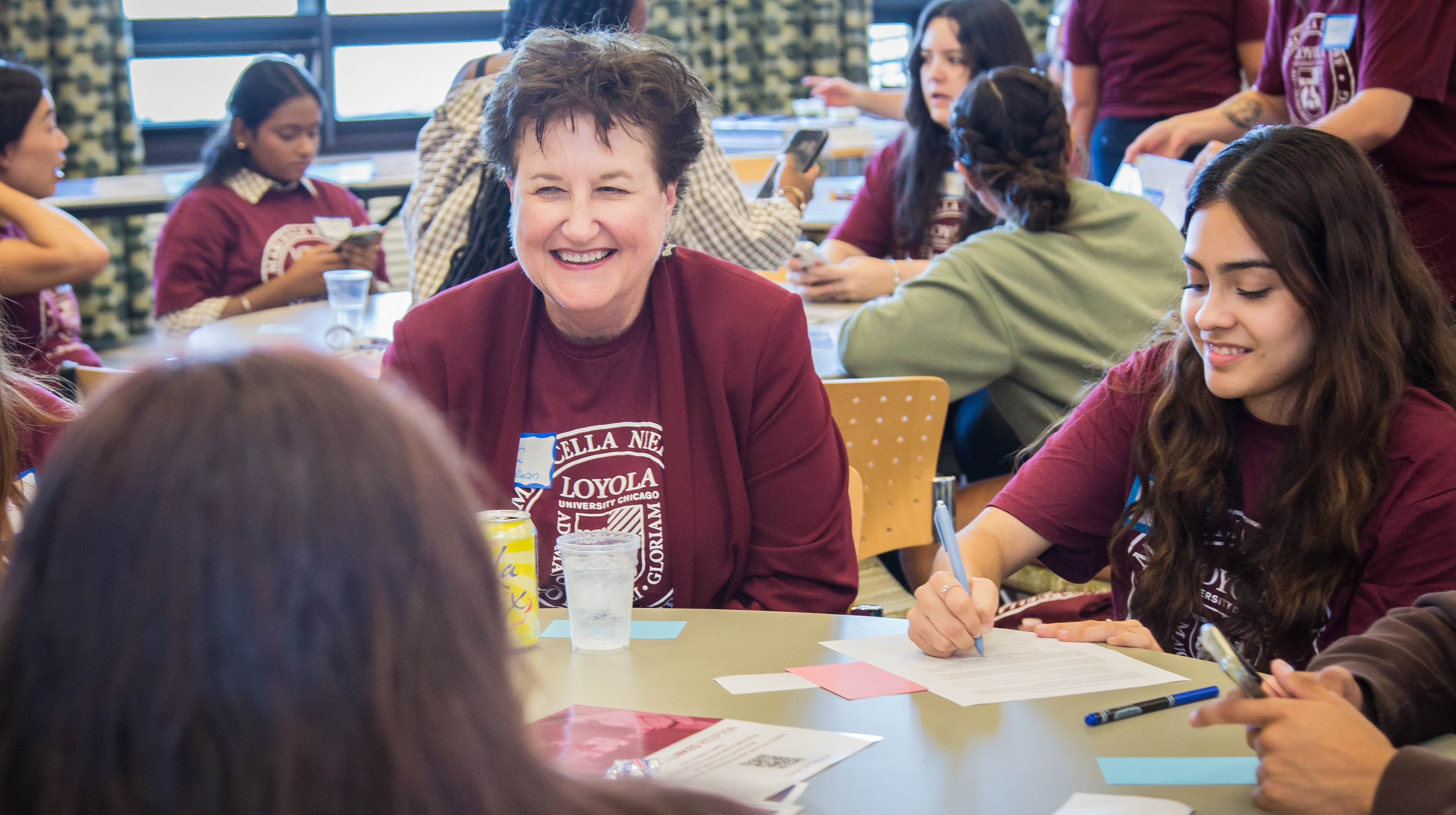 Dean Lorna Finnegan sits at a table with students and laughs